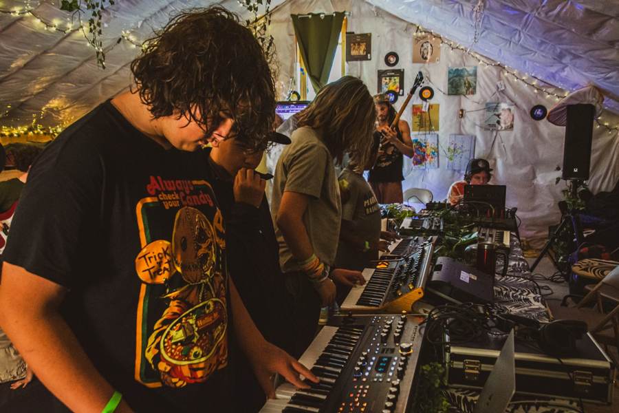 Campers playing a wall of synthesizers in the studio tent