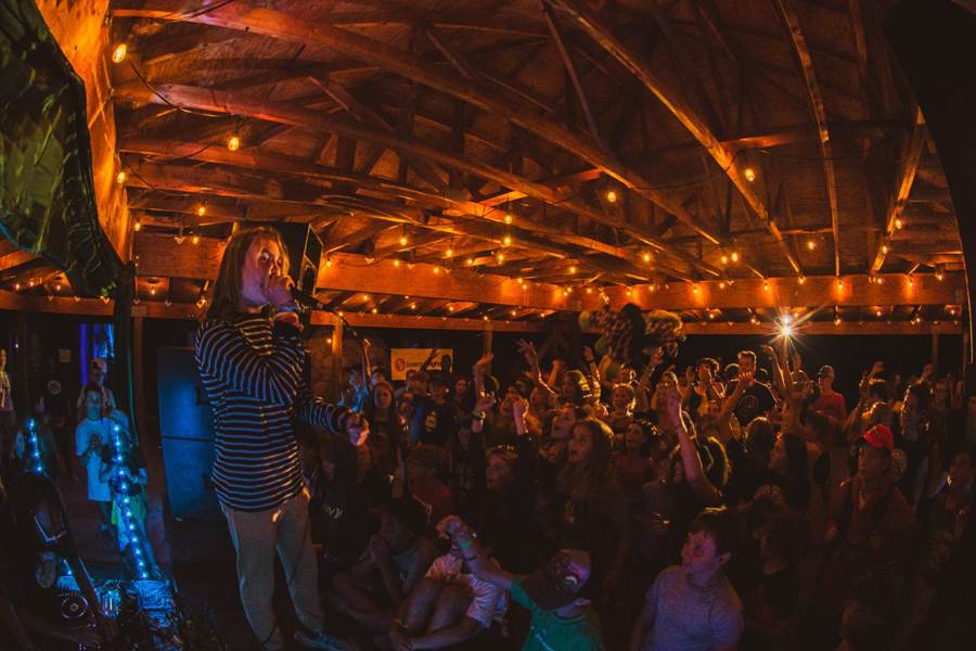 A camper performs on stage for a packed pavilion of cheering campers