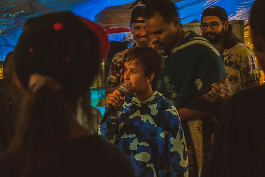 A camper raps into the mic while mentors cheer him on