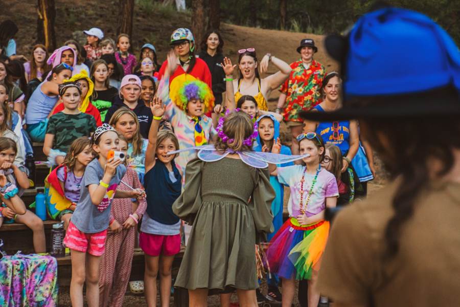 Campers in costumes and wigs cheering together on theme day